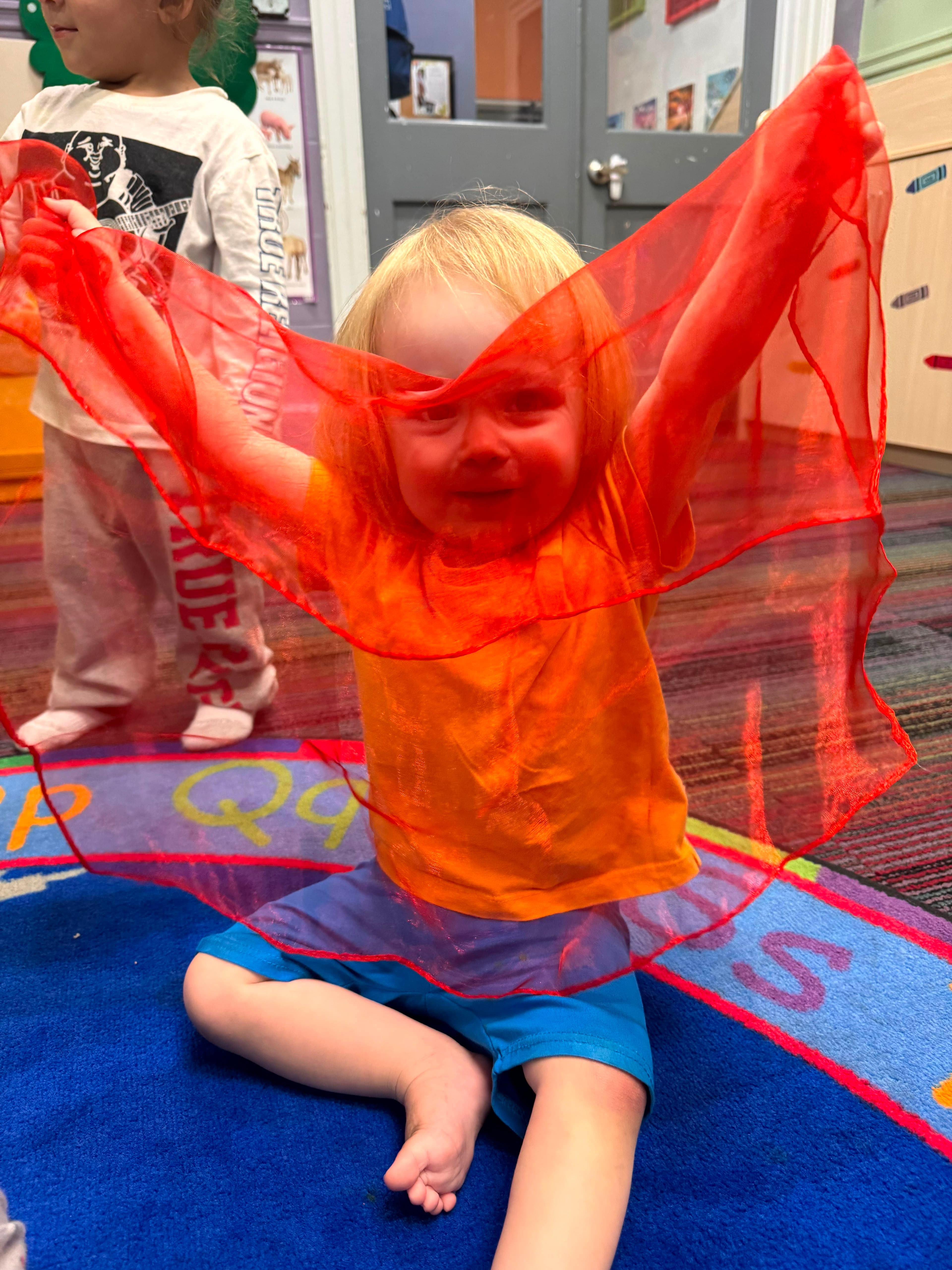 A child dancing with a bright red movement scarf at GCS