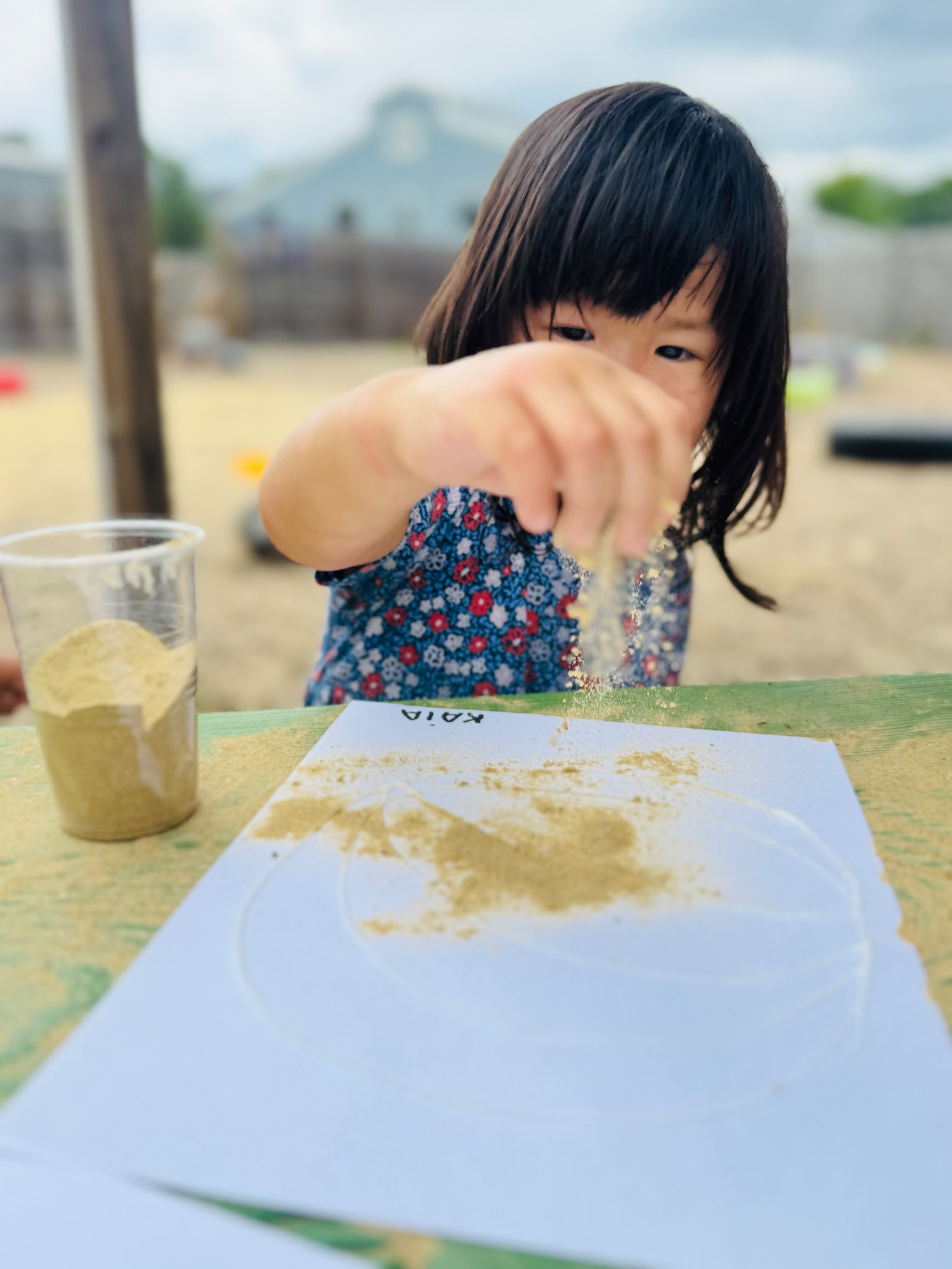 A child creating sand art during an outdoor GCS activity