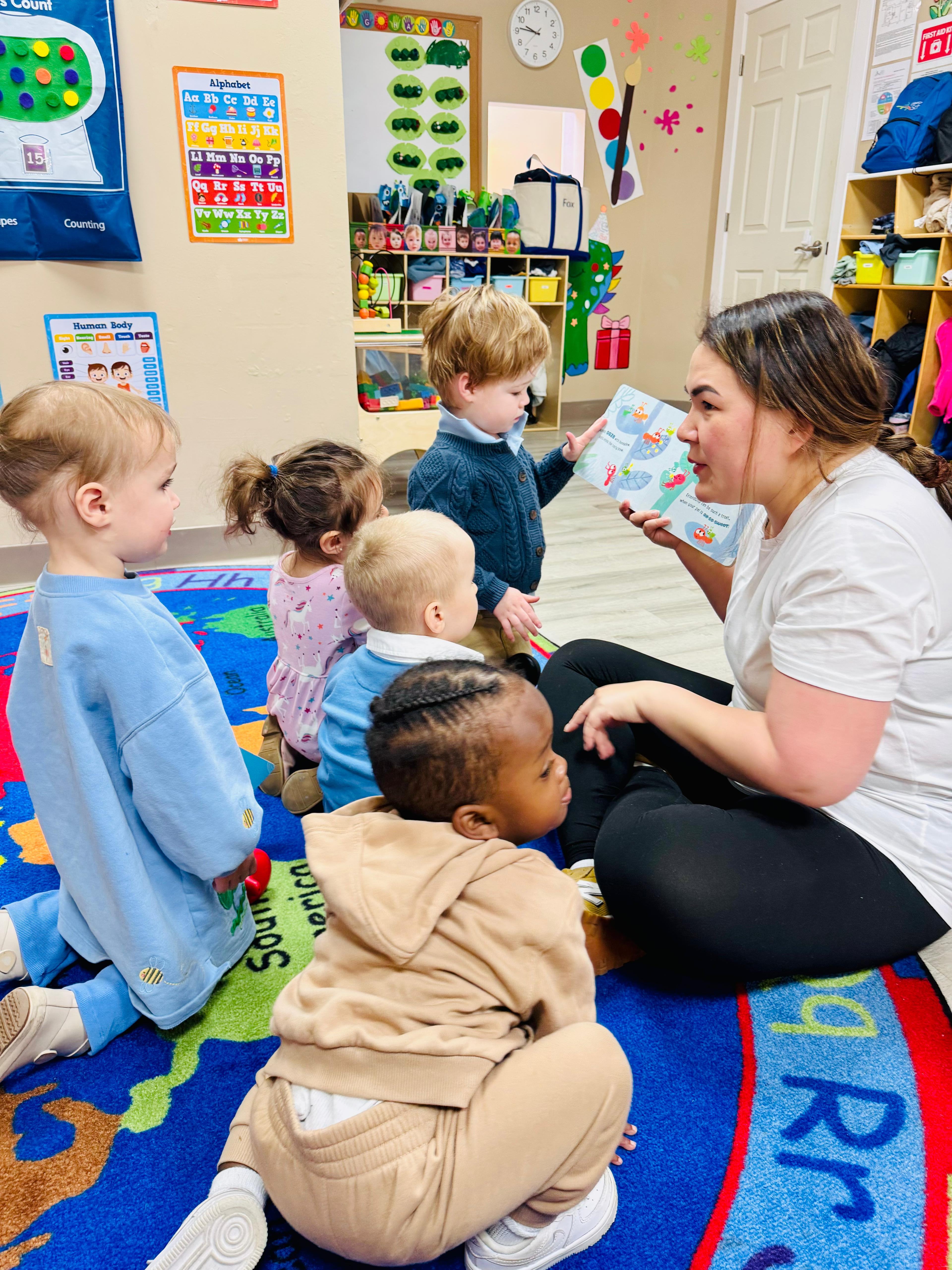 A GCS teacher reading with a group of toddlers