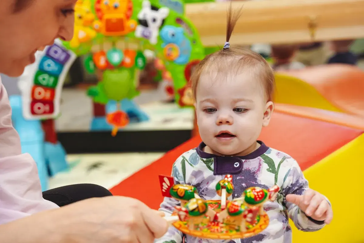 A GCS infant exploring an age-appropriate object with a trusted teacher